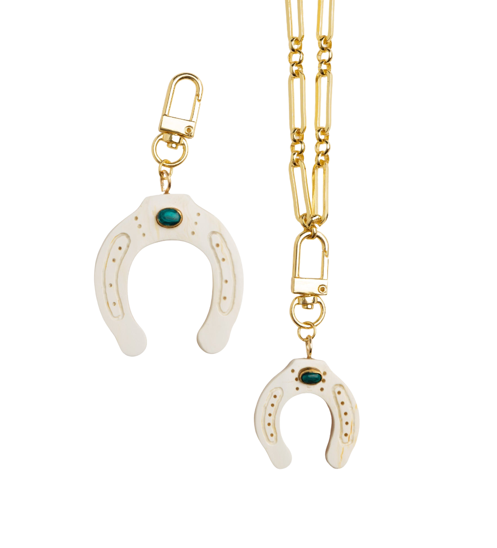 Gold necklace with white horseshoe pendant on a white background