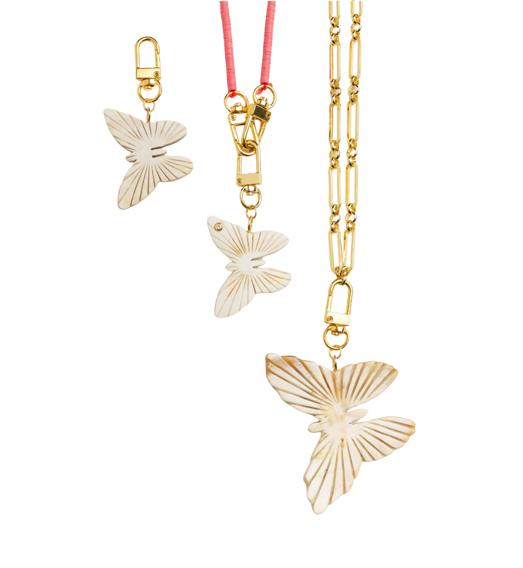 Butterfly-shaped gold pendant on a chain with a pink ribbon against a white background