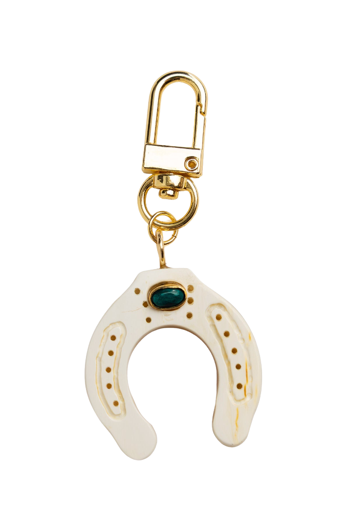 Horseshoe-shaped keychain with gold clasp and green gemstone on a white background