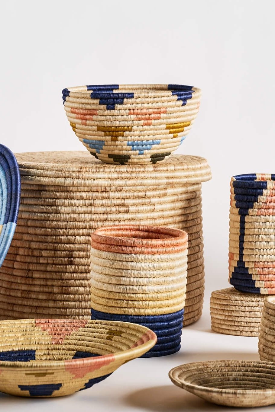 A vibrant fruit bowl featuring a blend of navy blue, cielo blue, salmon pink, olive green, and natural colors. Made from 100% natural fique, this handcrafted piece from Guacamayas, Colombia, adds a lively Caribbean touch to any table or shelf. Dimensions: 15 x 25 cm.