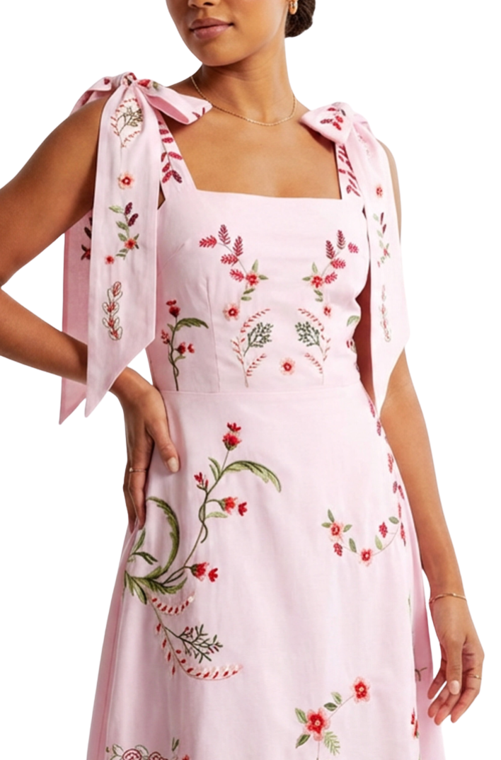Woman wearing a pink floral dress with a matching scarf on a white background