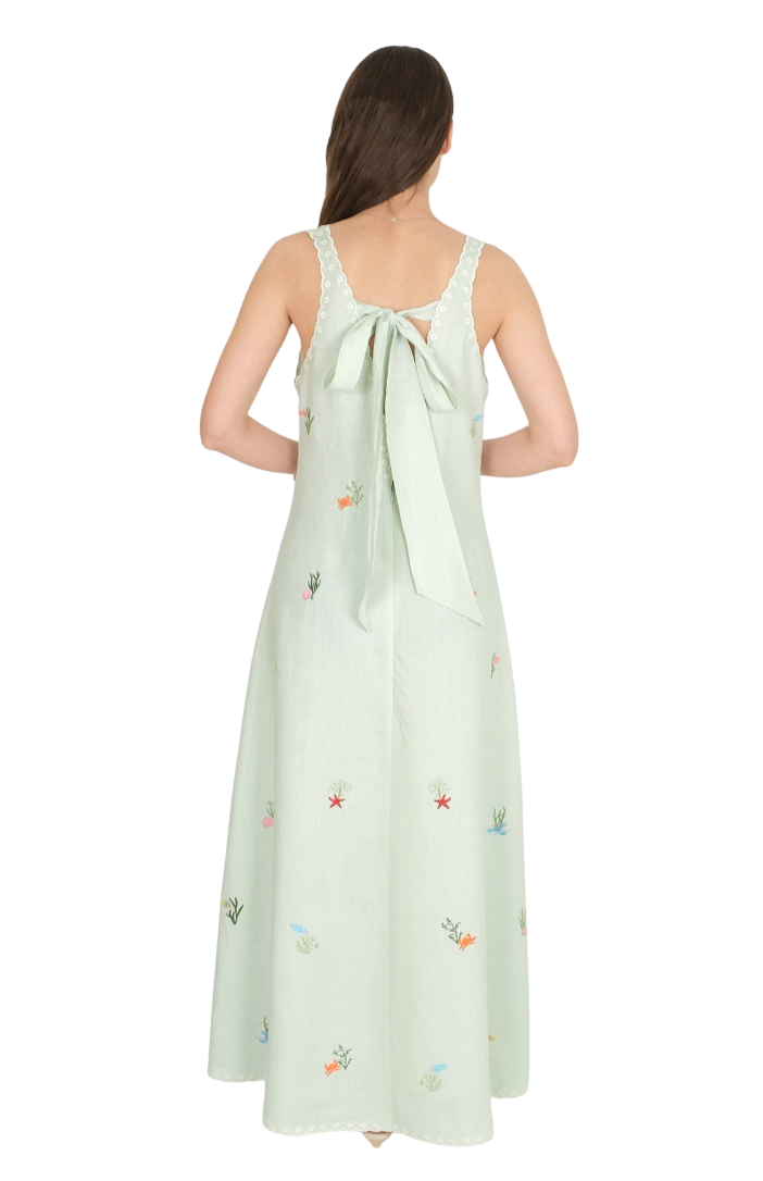 Woman wearing a light green dress with floral embroidery on a white background