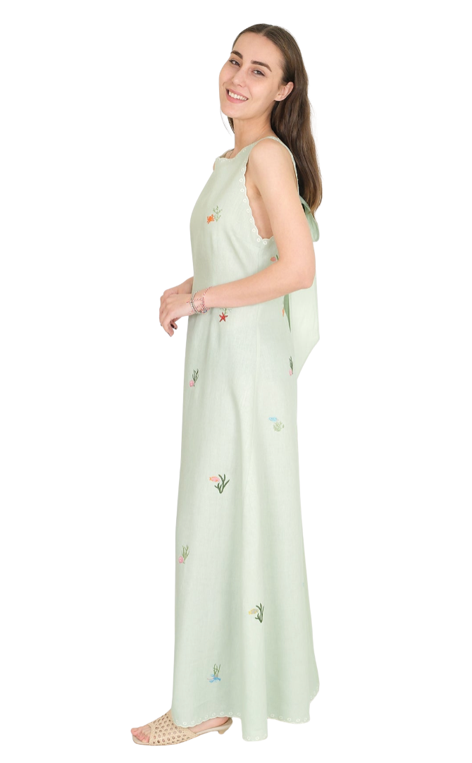 Woman wearing a mint green sleeveless dress with floral embroidery on a white background