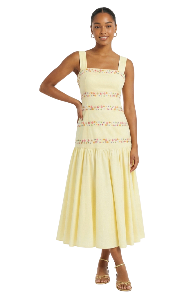 Woman wearing a yellow dress with floral lace details on a white background