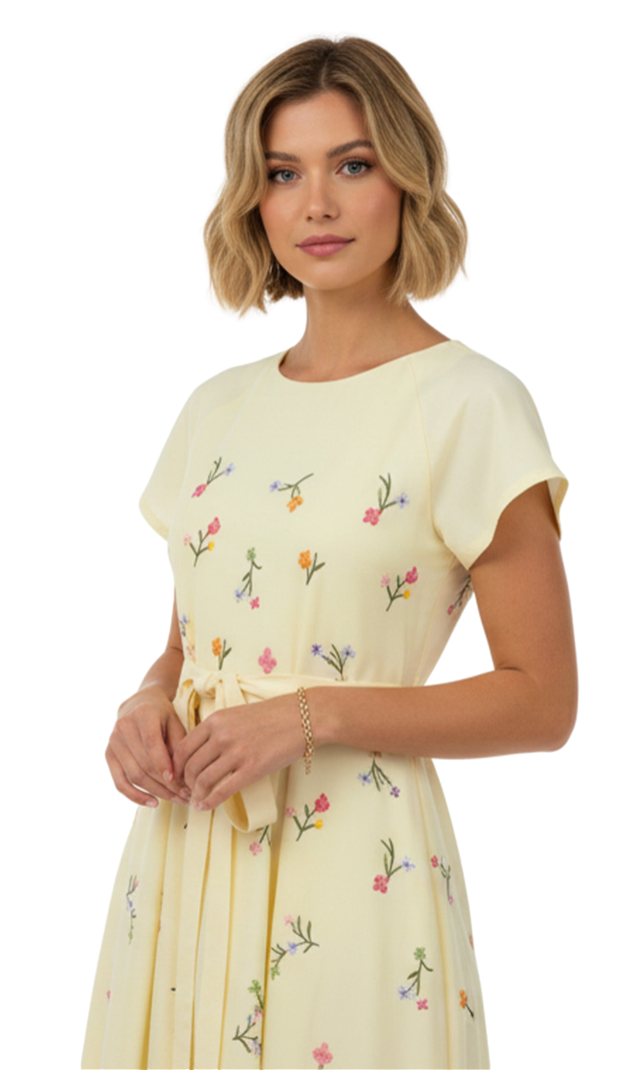 Woman wearing a light yellow dress with floral embroidery on a white background