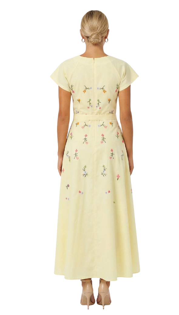 Woman wearing a light yellow dress with floral pattern on a white background