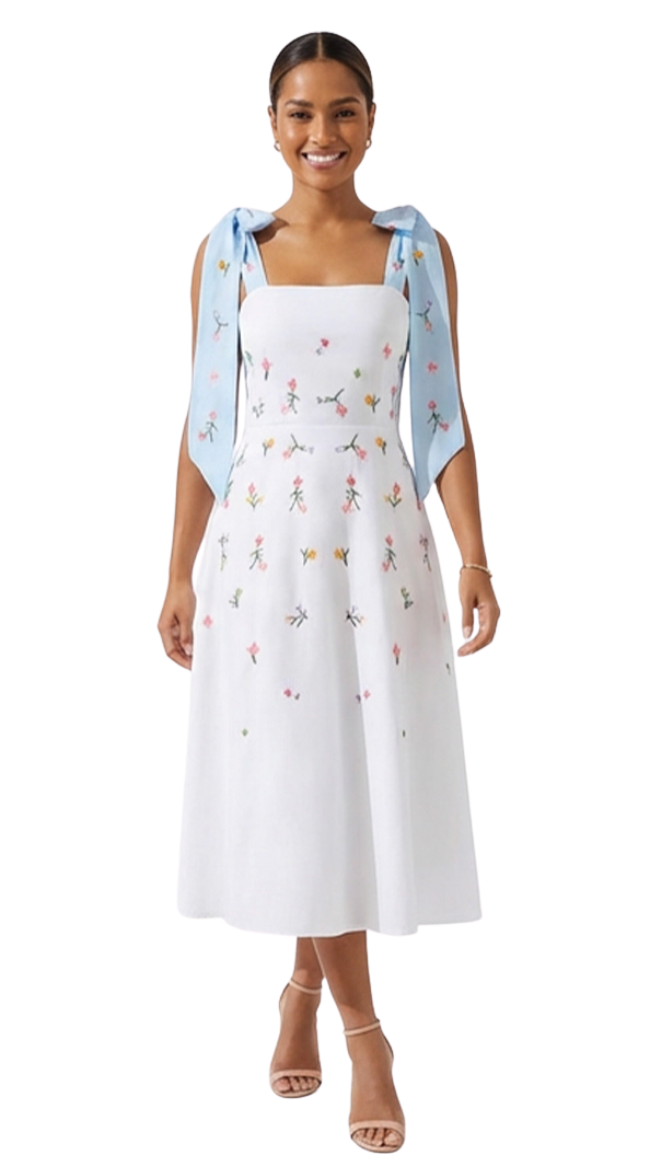 Woman wearing a white dress with floral patterns and a light blue cardigan on a white background