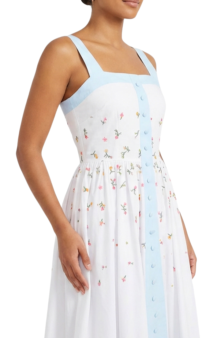Woman wearing a white dress with floral pattern and light blue straps on a white background