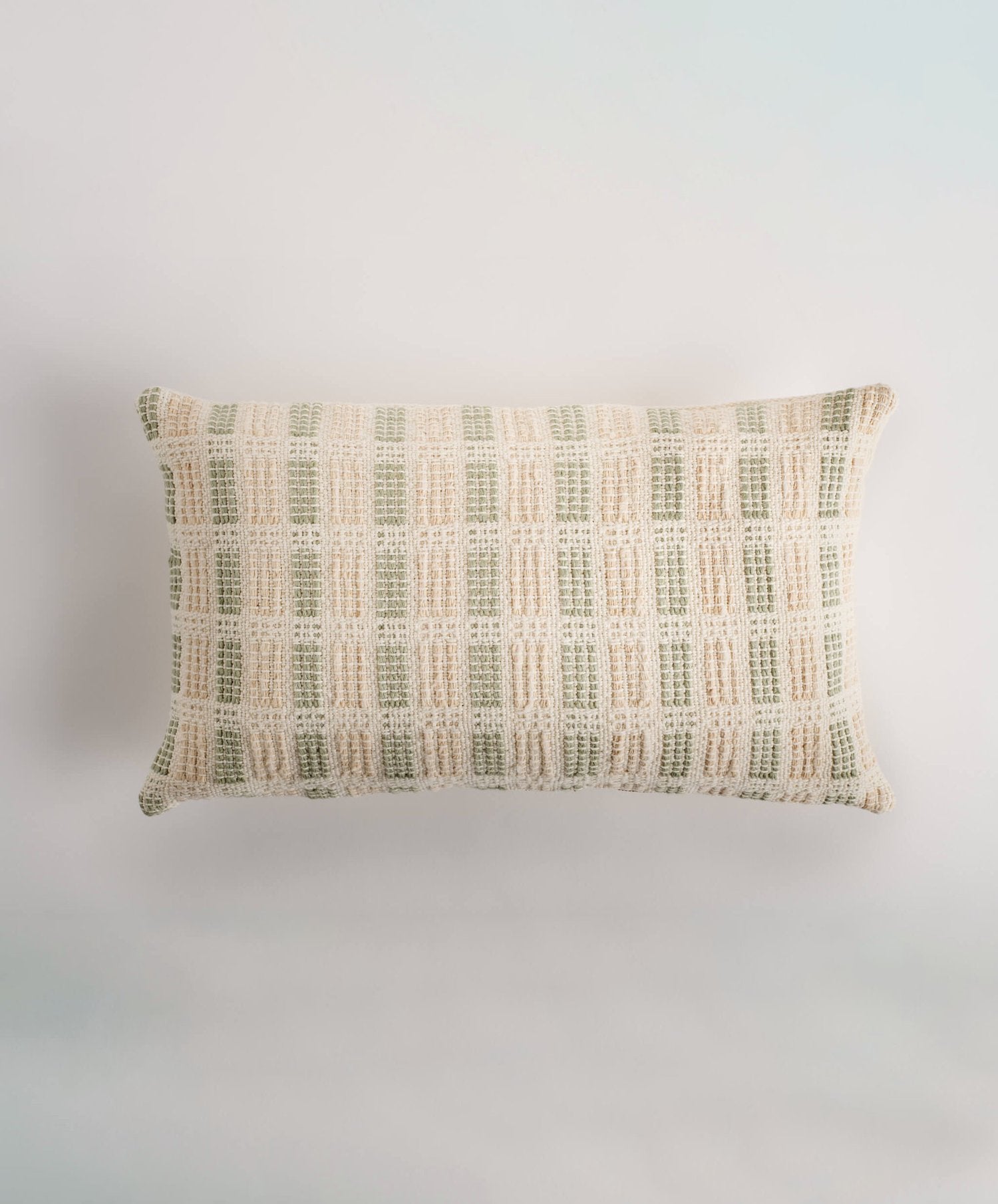 Decorative pillow cover in two color options: Sage Green & Cream and Earth Brown & Cream. The cover measures 30 x 50 cm (12 x 20 inches) and is crafted from 100% organic cotton, featuring both undyed and naturally dyed handspun and industrially spun yarn. A golden metal zipper pull adds a touch of elegance. The back is made from plain weave organic cotton in natural cotton. Insert not included. Handmade by a women artisan cooperative in Charalá, Colombia.