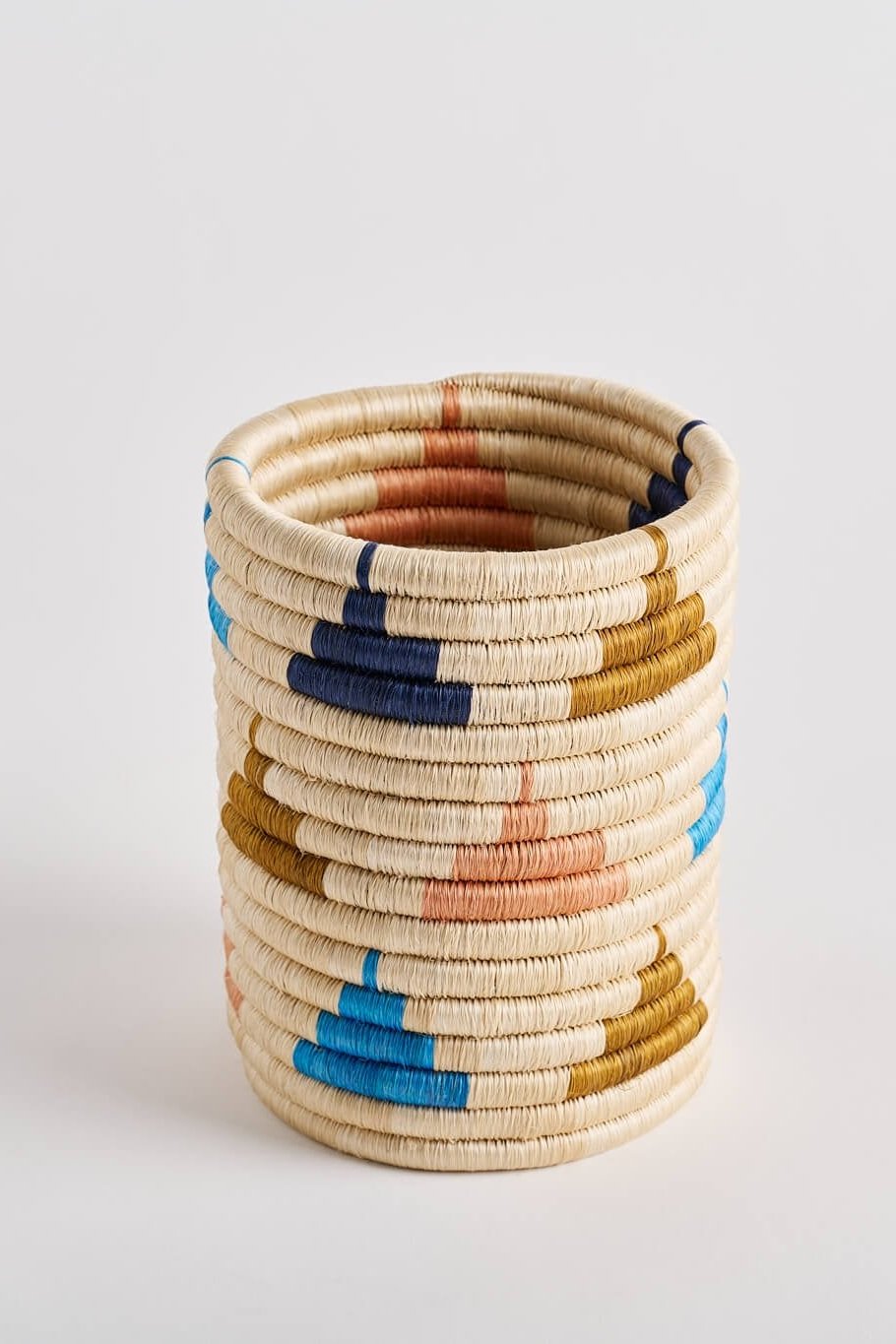 Versatile tabletop basket in vibrant colors: Navy Blue, Cielo Blue, Salmon Pink, Olive Green, and Natural. Measuring 15 x 20 cm (6 x 8 inches), this basket is crafted from 100% natural un-dyed and dyed fique from Colombia. Perfect for use as countertop decor, an utensil holder, or a vase. Handmade by an artisan cooperative in Guacamayas, Boyacá, Colombia, showcasing the bright colors inspired by the Caribbean