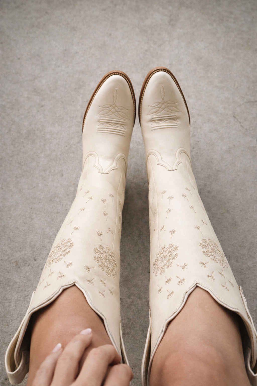 White cowboy boots with floral patterns on a gray surface