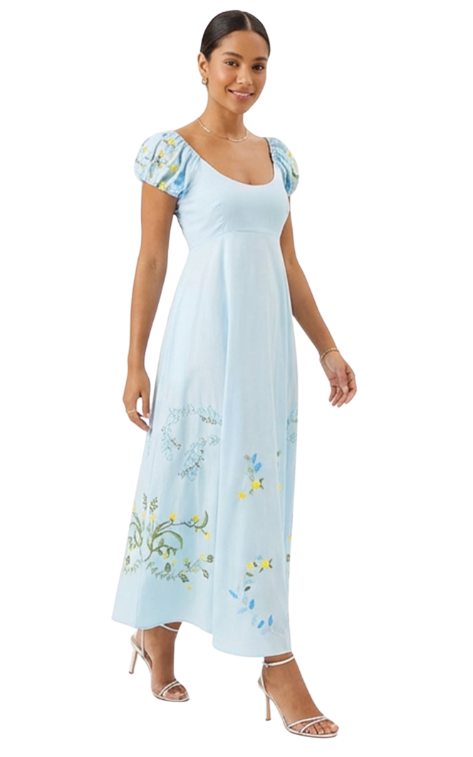 Woman wearing a light blue dress with floral embroidery on a white background