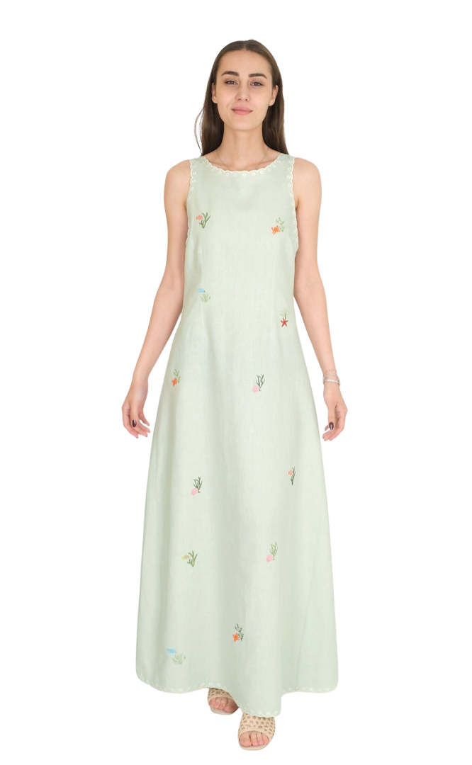 Woman wearing a light green sleeveless dress with floral patterns on a white background