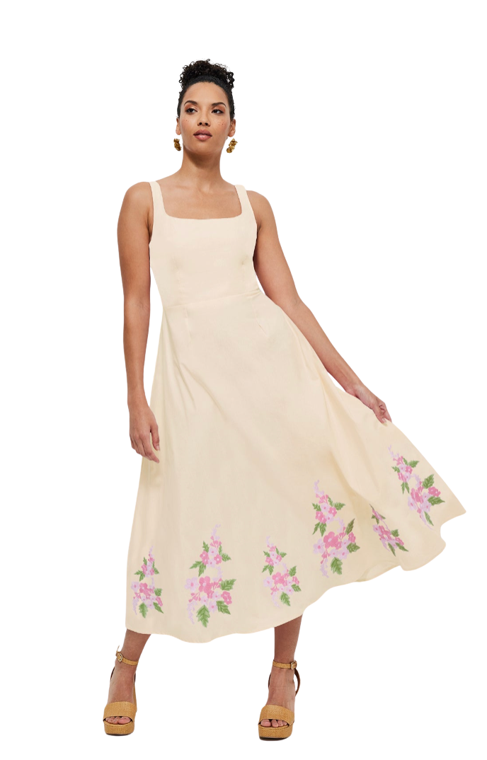 Woman wearing a beige dress with floral embroidery on a white background