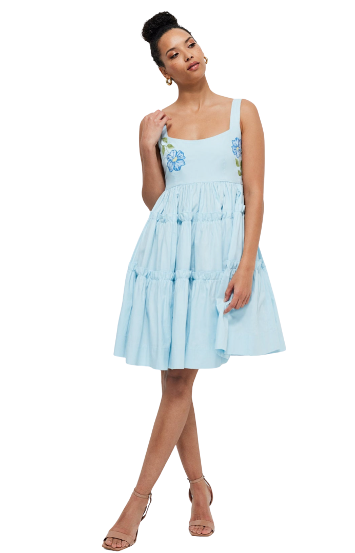 Woman wearing a light blue dress with floral patterns on a white background