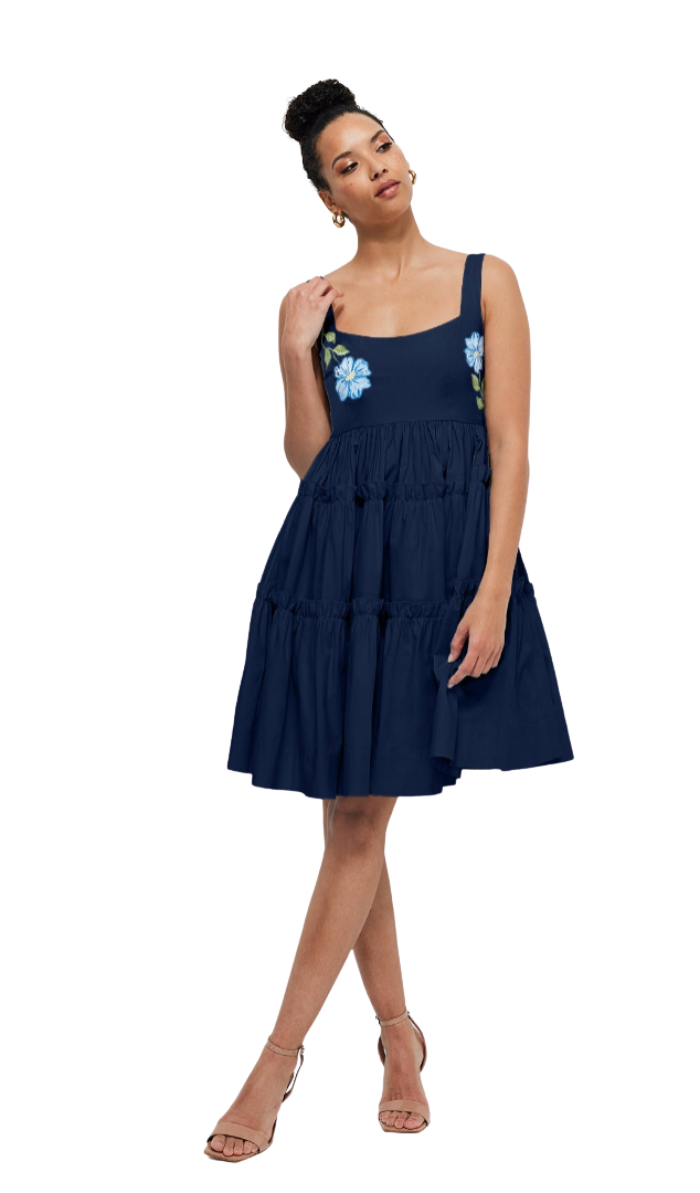 Woman wearing a navy dress with floral embellishments on a white background
