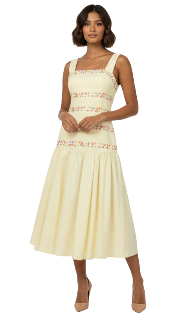 Woman wearing a light yellow dress with floral lace details on a white background