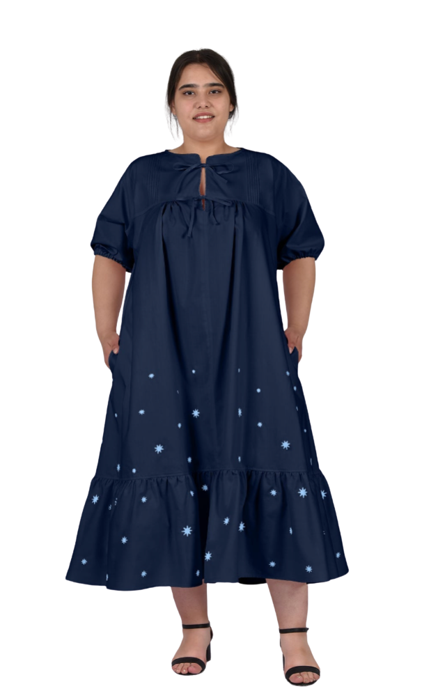 Woman wearing a navy blue dress with white patterns on a white background
