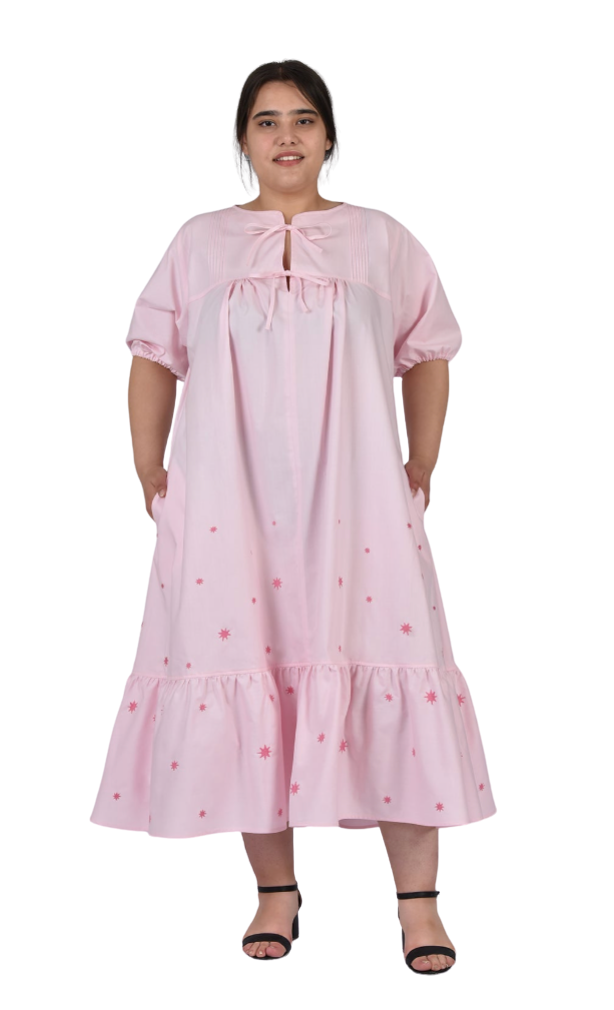 Woman wearing a pink dress with floral embroidery on a white background