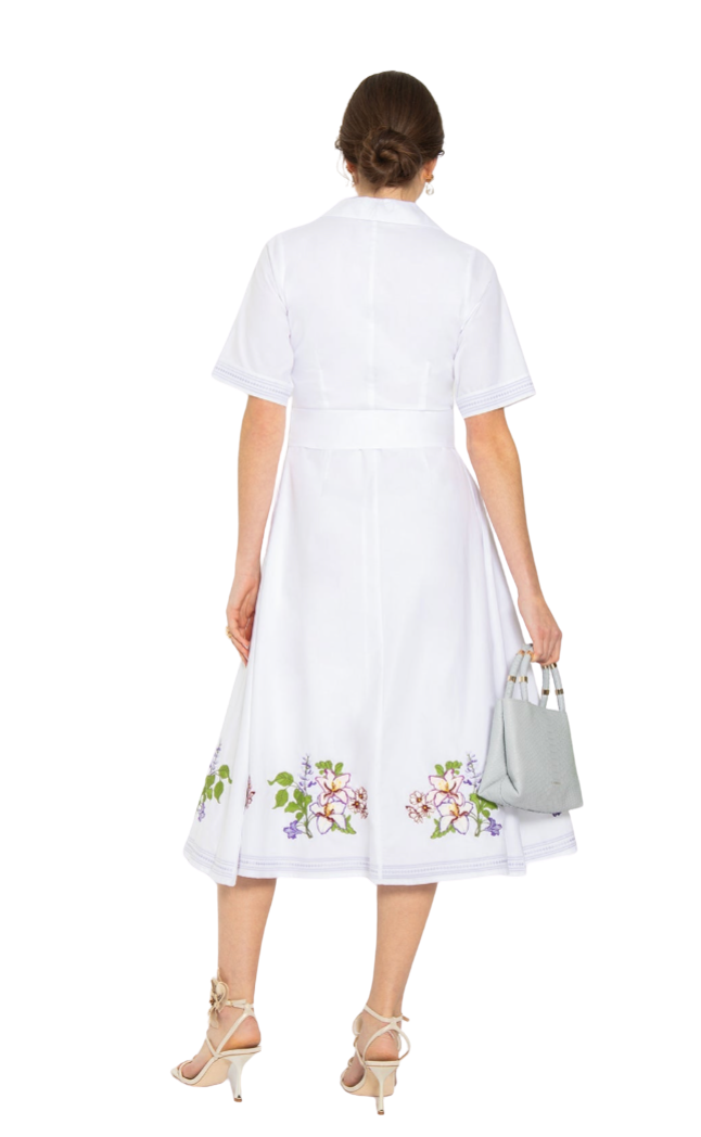 Woman wearing a white dress with floral embroidery on a white background