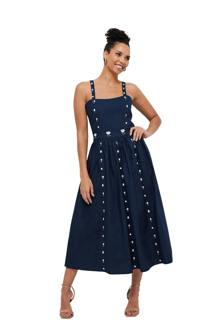 Woman wearing a navy blue dress with white embellishments on a white background