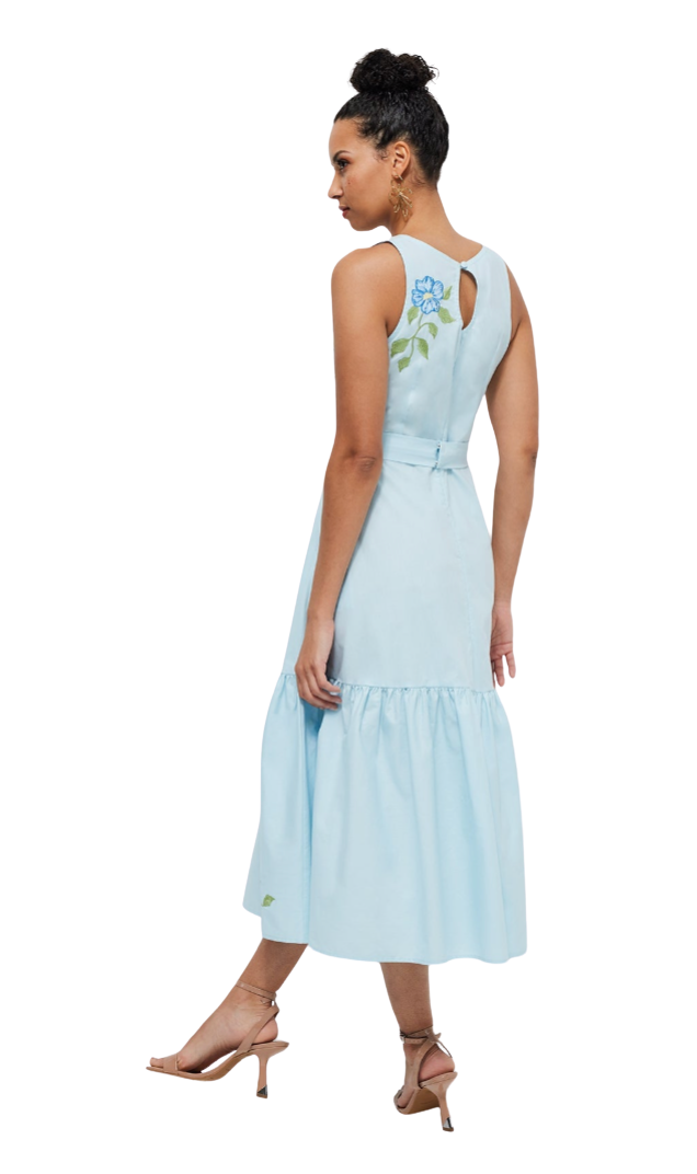 Woman wearing a light blue dress with floral details on a white background