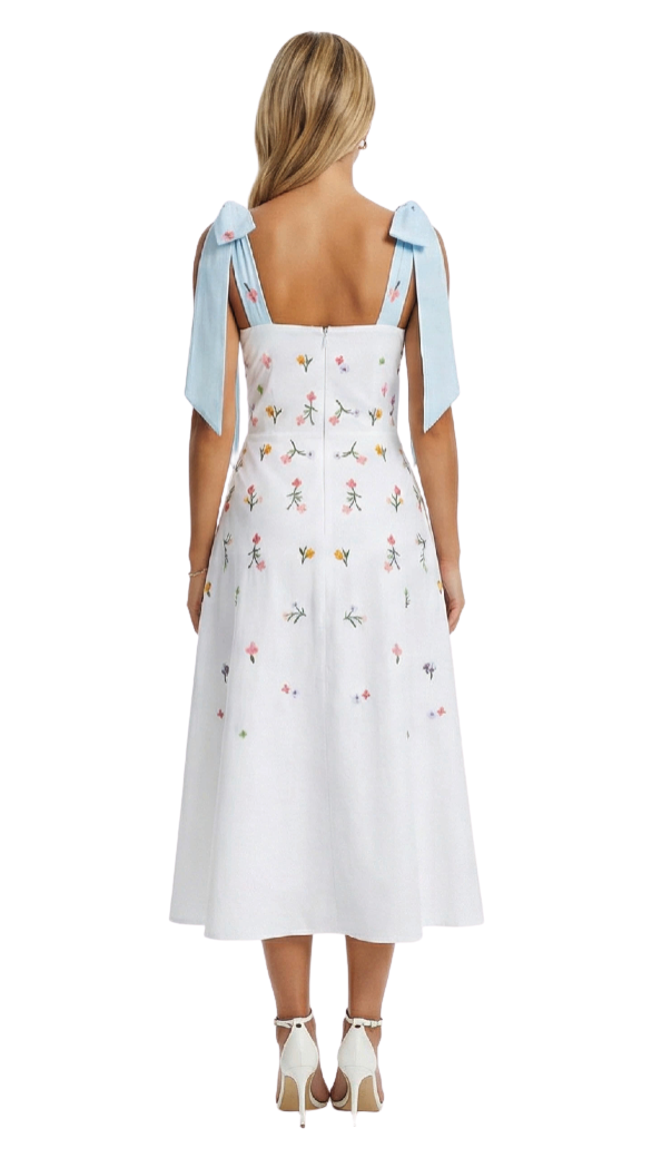 White dress with floral pattern and blue ribbon straps worn by a model on a white background