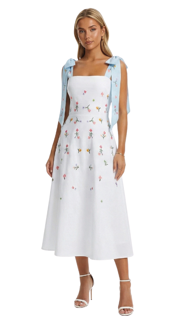 Woman wearing a white dress with floral embroidery and a blue cardigan on a white background