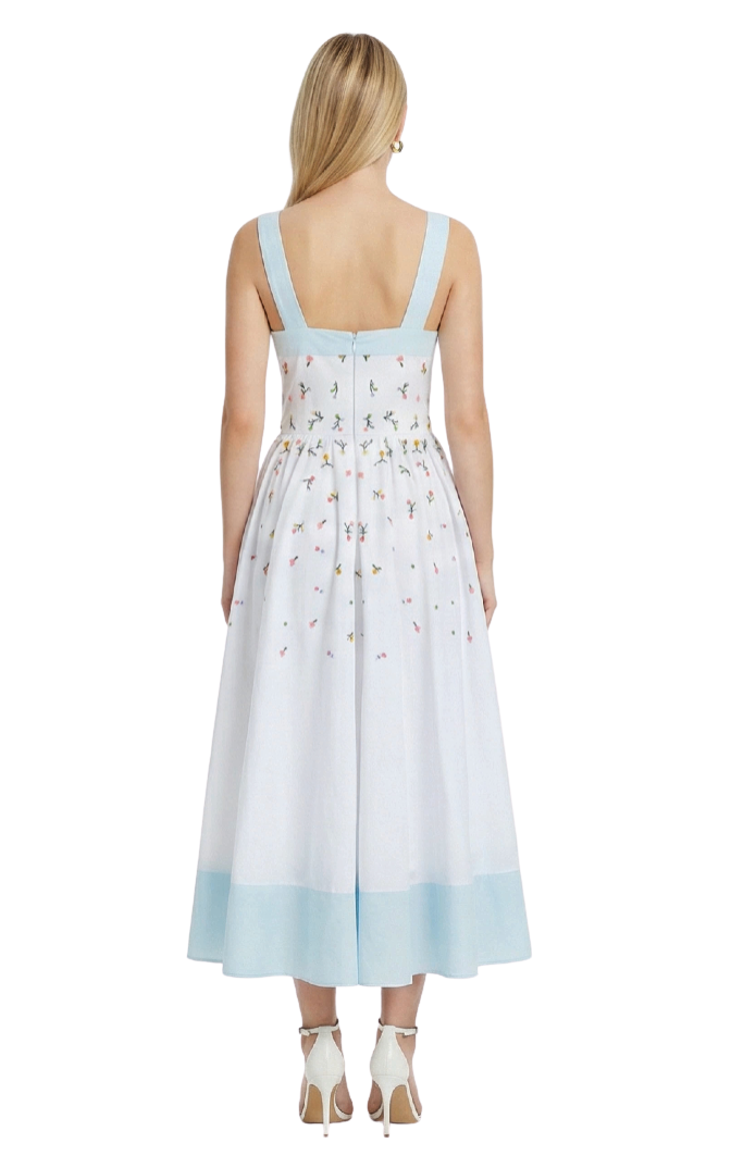 Woman wearing a light blue and white dress with floral pattern on a white background