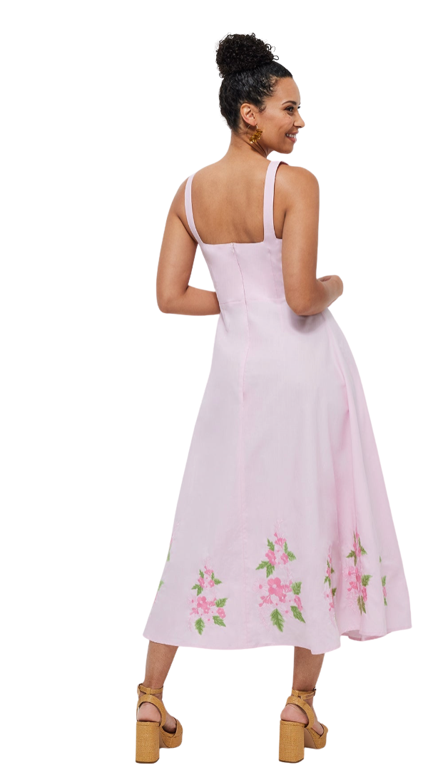 Woman wearing a light pink dress with floral embroidery on a white background