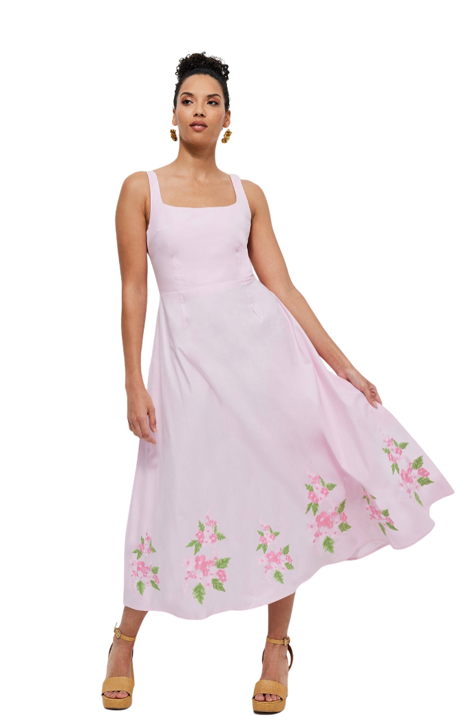 Woman wearing a light pink dress with floral embroidery on a white background