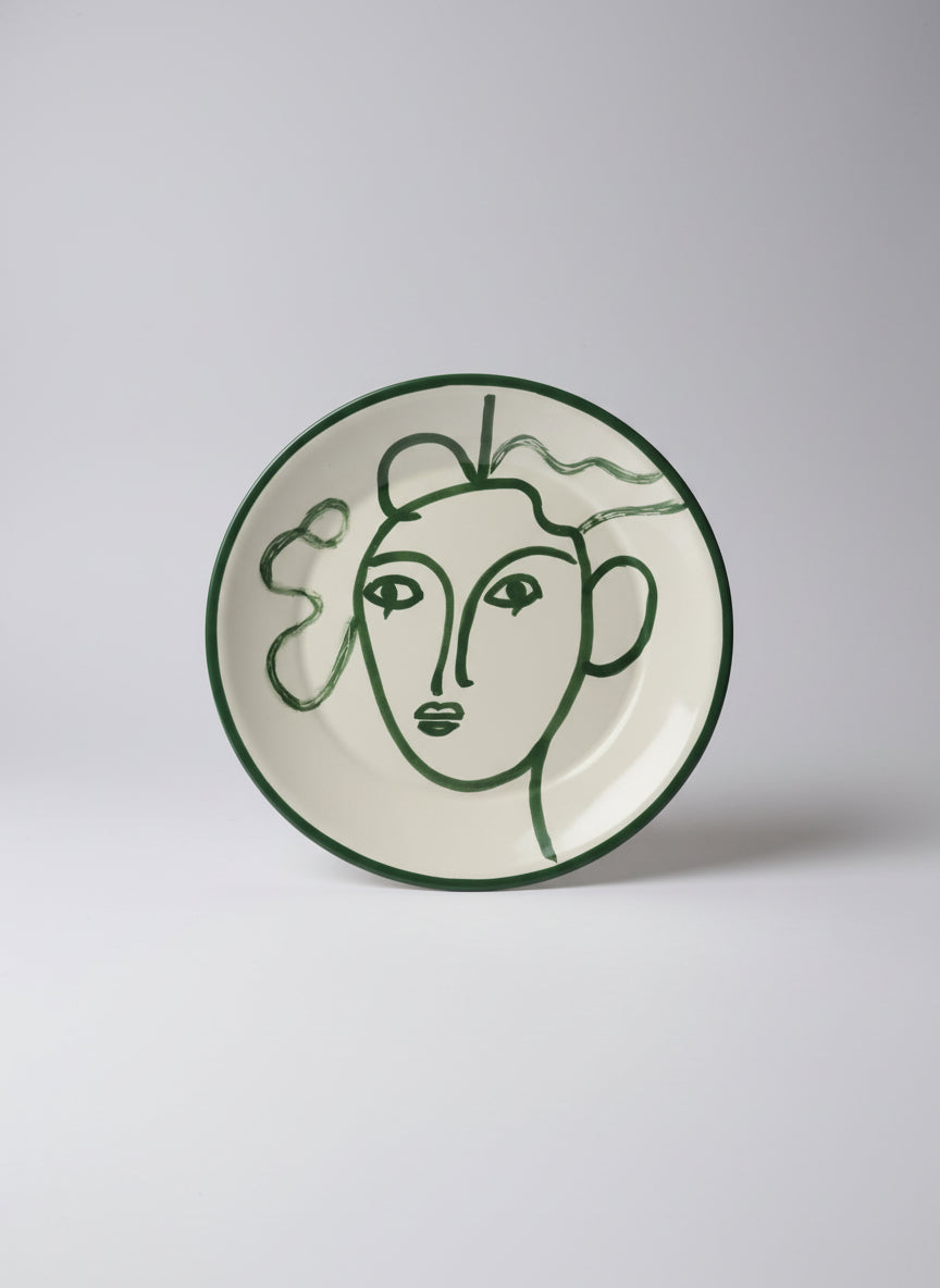 Round green and white object with a stylized face design on a reflective surface.