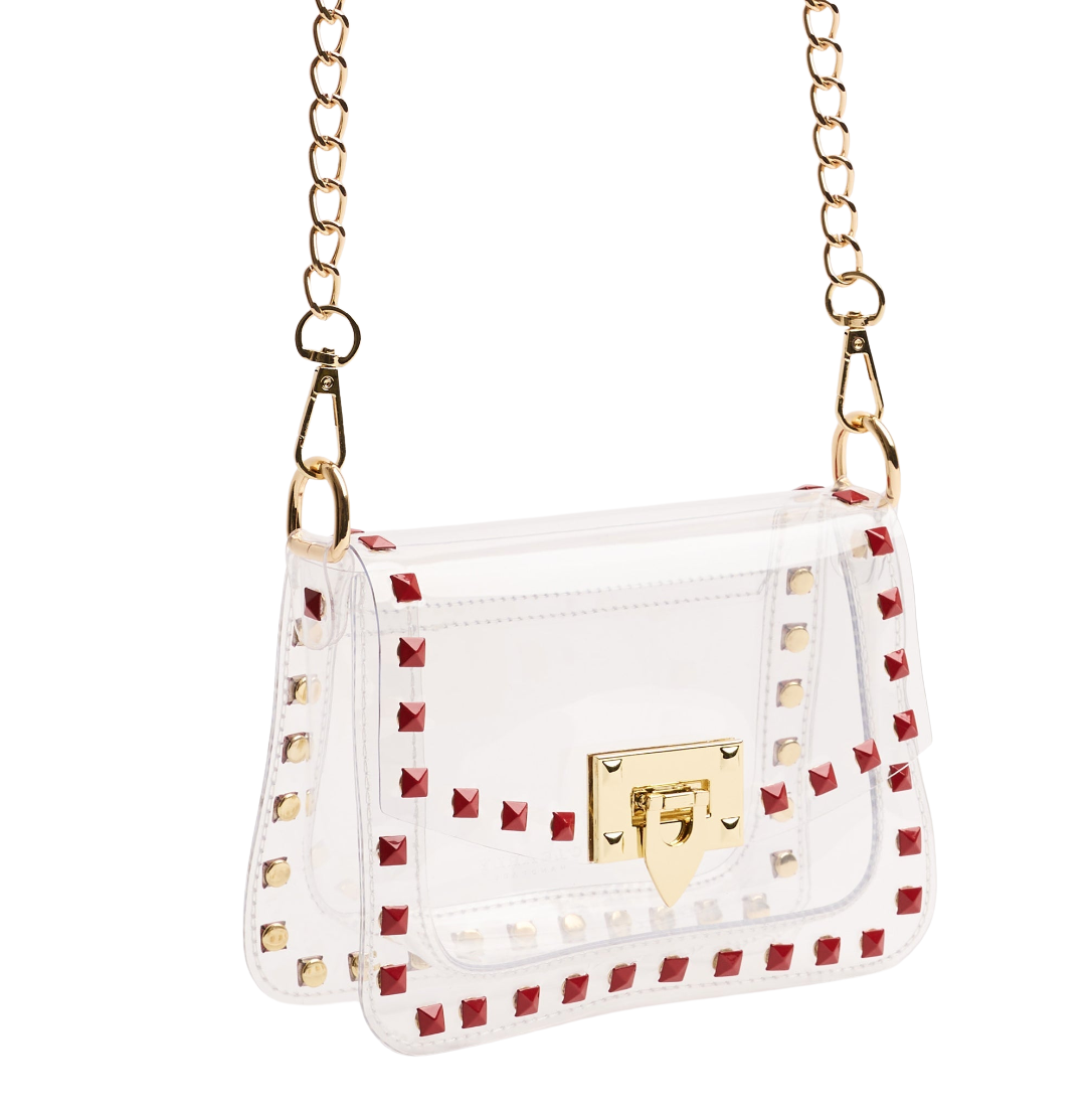 A white faux leather shoulder bag with red and gold pyramid studs, a gold turn-lock clasp, and a gold chain strap, shown against a plain white background.