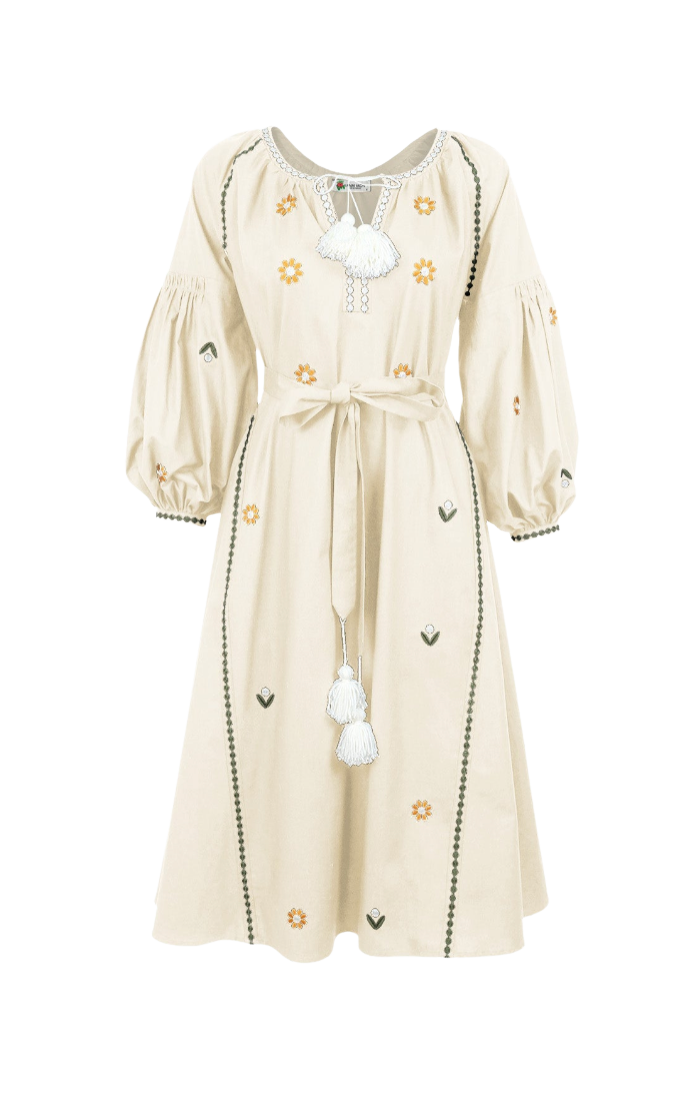 A cream-colored long-sleeve dress with embroidered floral and leaf patterns, featuring a tie waist and decorative tassel, shown against a plain white background.