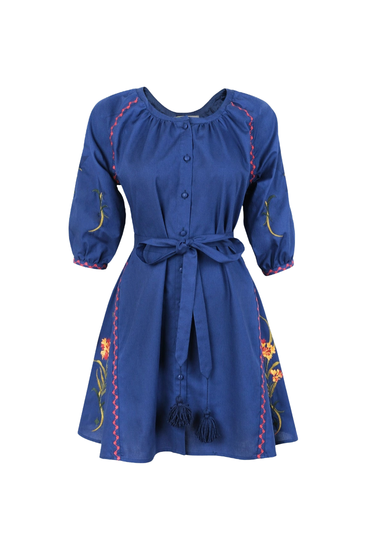 A blue cotton dress with three-quarter sleeves, a button-up front, a matching waist tie, and colorful floral embroidery with tassel details, shown on a plain white background.