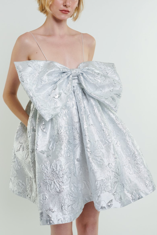 silver metallic babydoll dress with adjustable spaghetti straps and a voluminous skirt, featuring an intricate jacquard pattern.