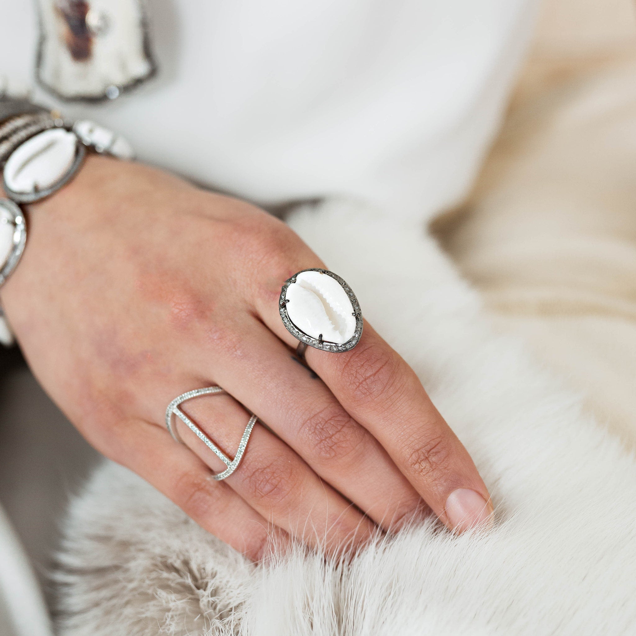 Hand wearing a silver ring with a large gemstone on a soft surface