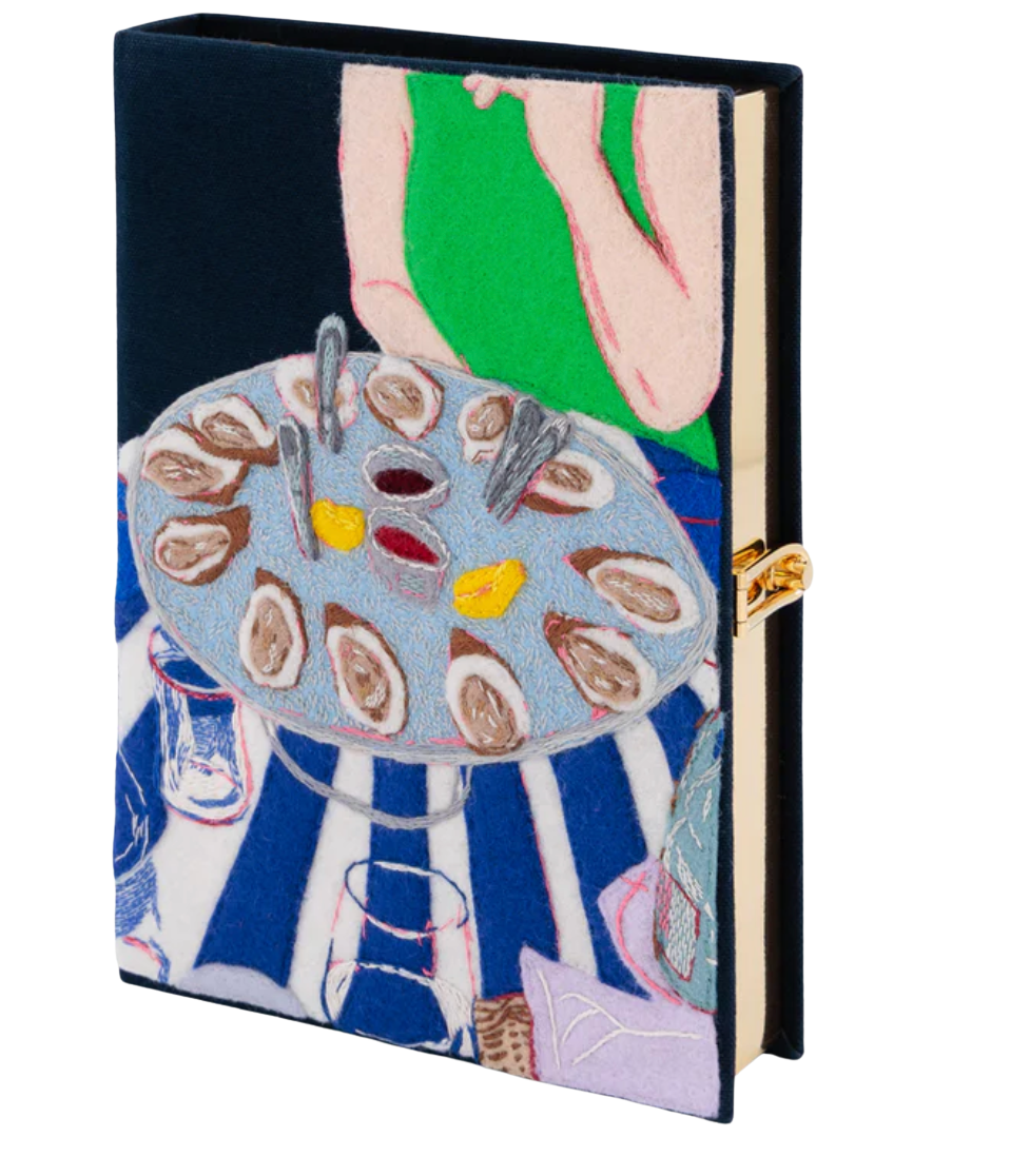 A hardcover notebook or journal with a colorful embroidered cover depicting a person and a table of oysters, shown on a plain white background.