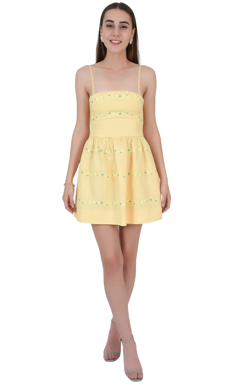 Woman wearing a yellow dress with floral embellishments on a white background