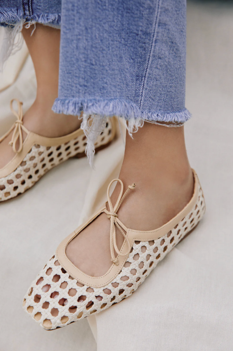 Beige ballet flats with cut-out design worn with blue jeans on a light background